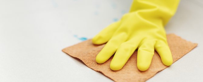Rubber glove hand drying a wet floor to prevent the growth of black mold during removal