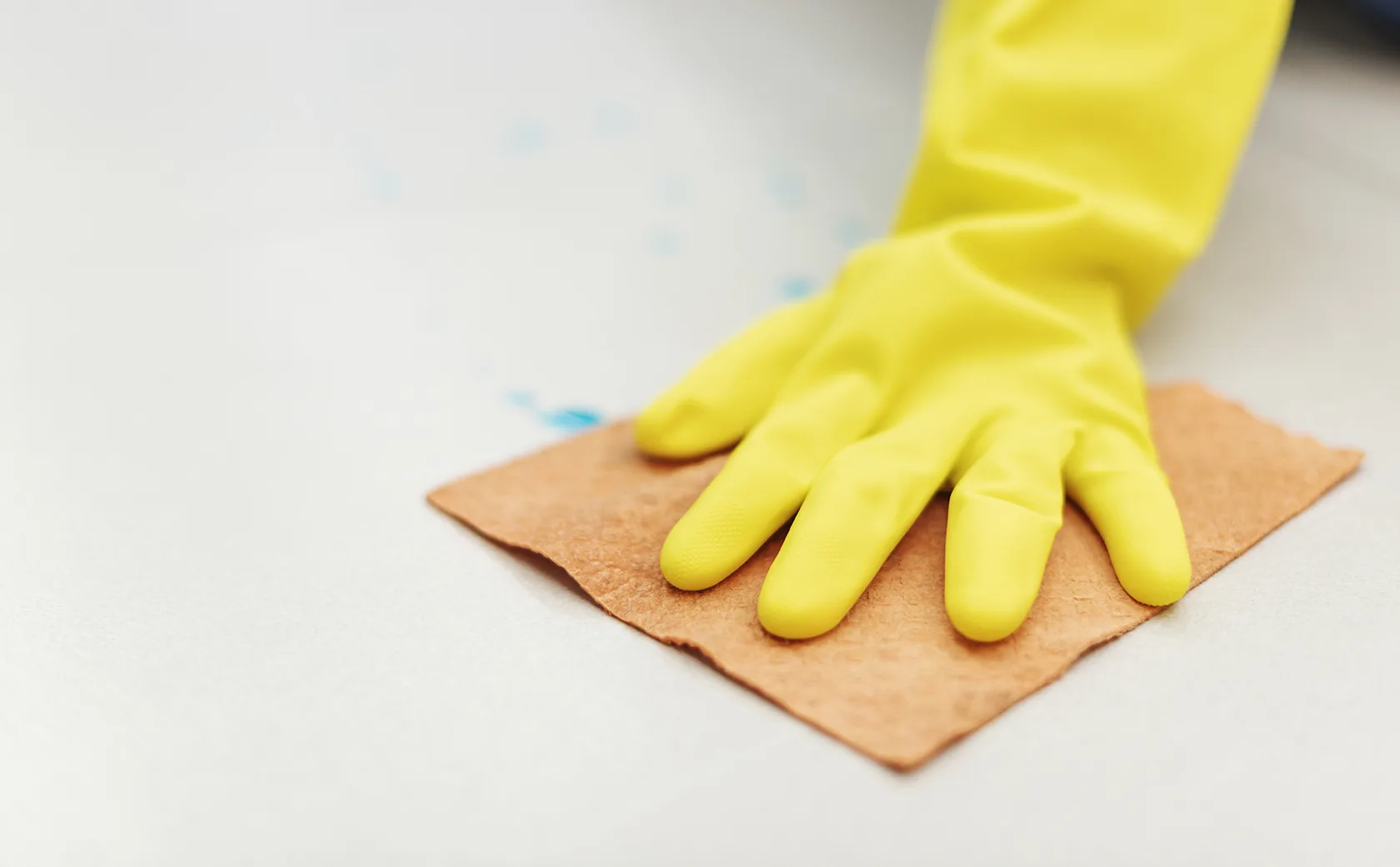 Rubber glove hand drying a wet floor to prevent the growth of black mold during removal