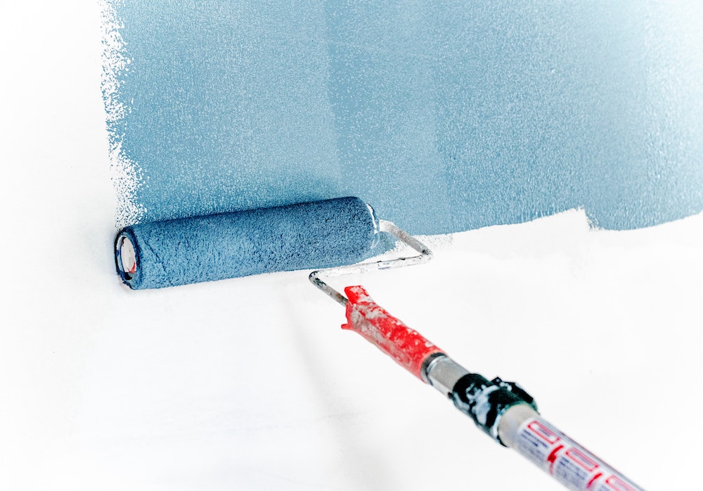 A paint roller painting a wall with mold resistant paint.